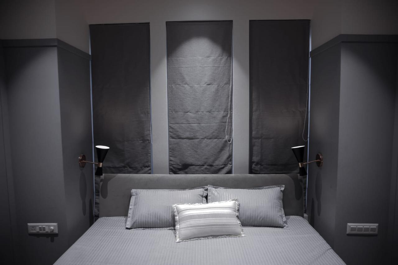 Minimalist grey bedroom with roman blinds and wall sconces